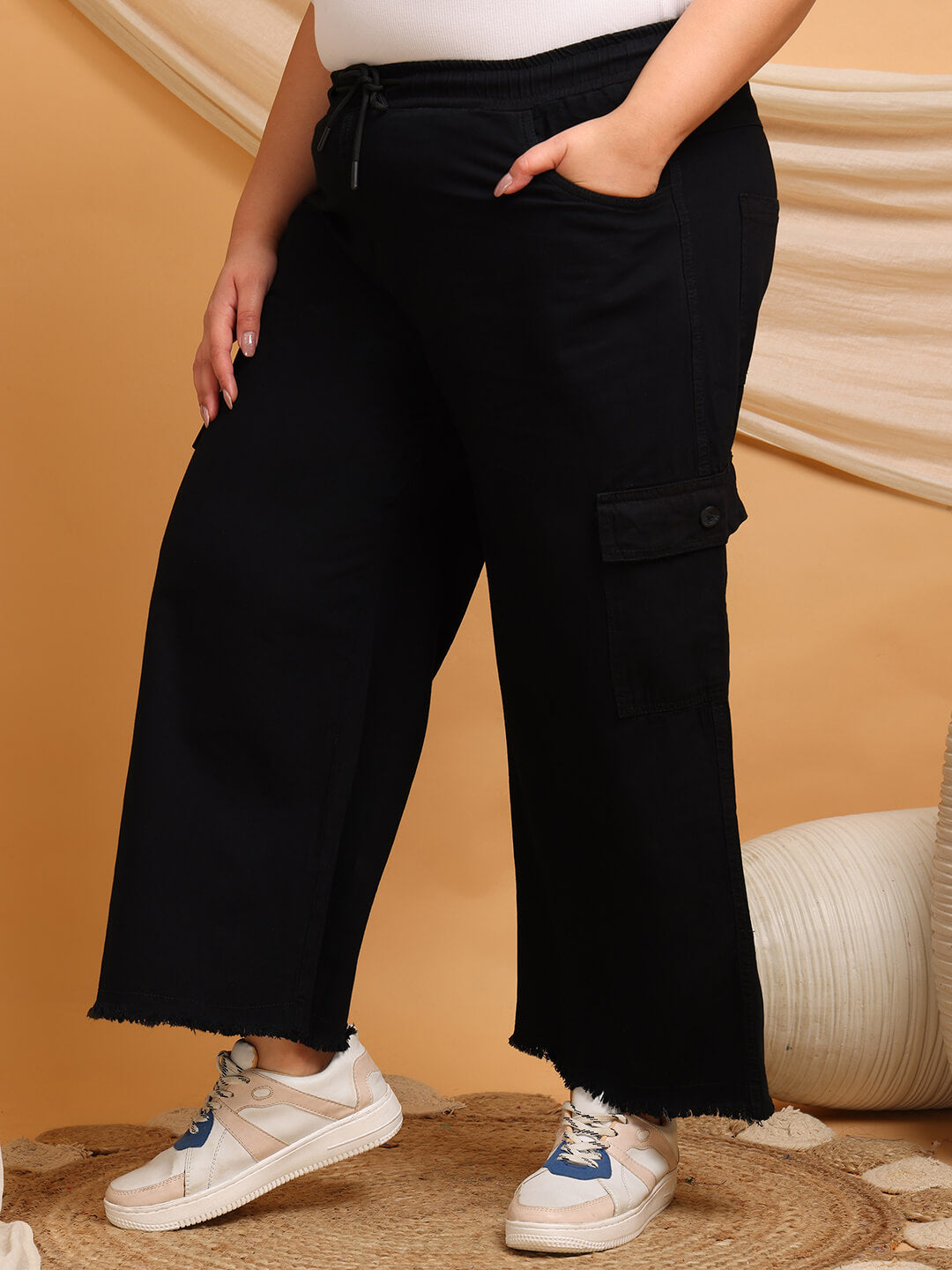 Close-up of black denim cargo pants showing drawstring waist and cargo pocket detail – Curvisha