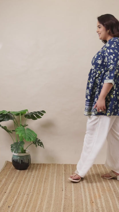 Plus size blue floral wrap tunic by Curvisha styled with white trousers for a flattering silhouette.