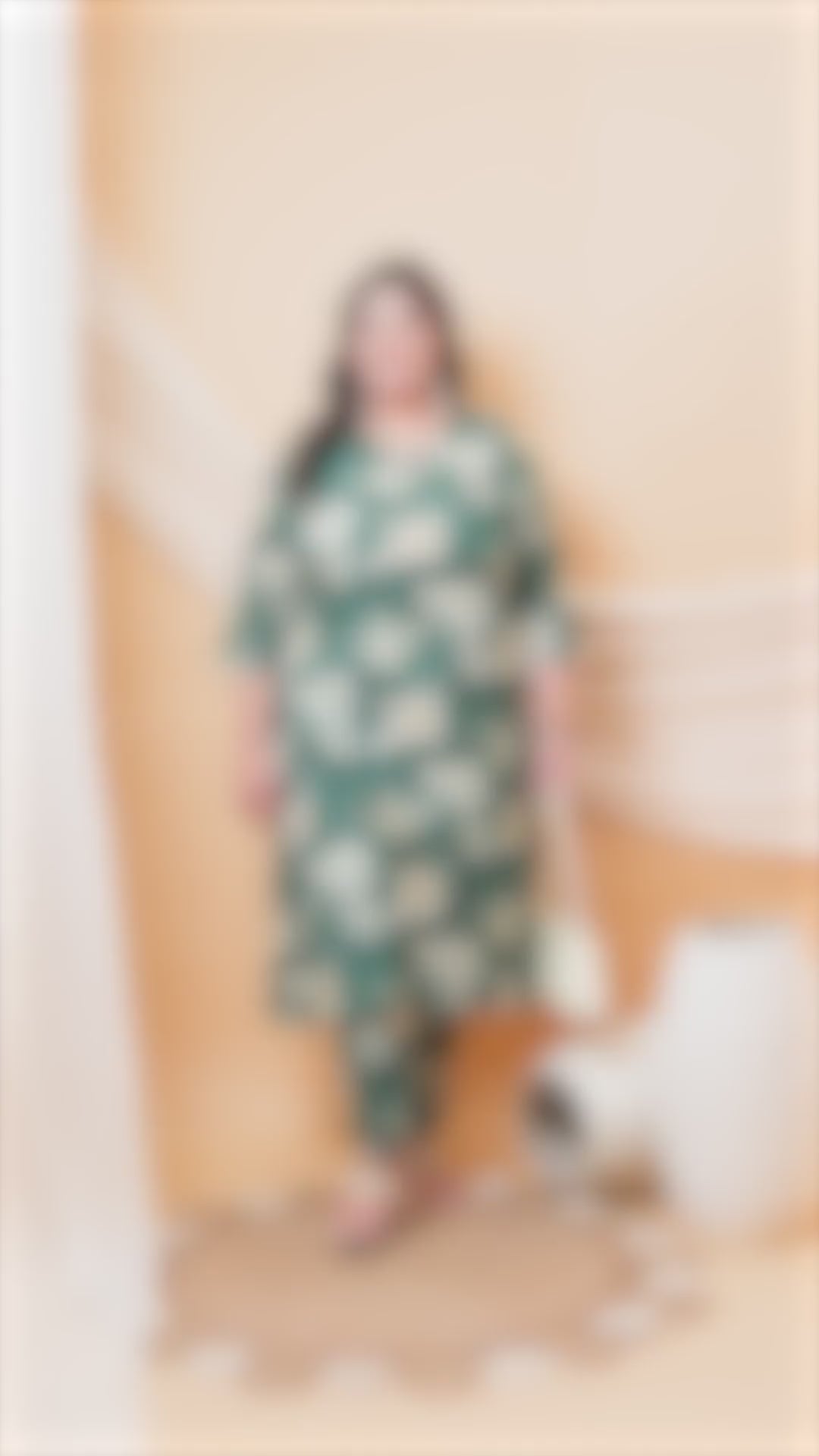 Plus-size model wearing an emerald green floral co-ord set with a V-neck tunic and matching trousers, styled with a white handbag.